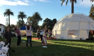 A group stretches outside the “Welcome” dome, as Peter Russell walks by